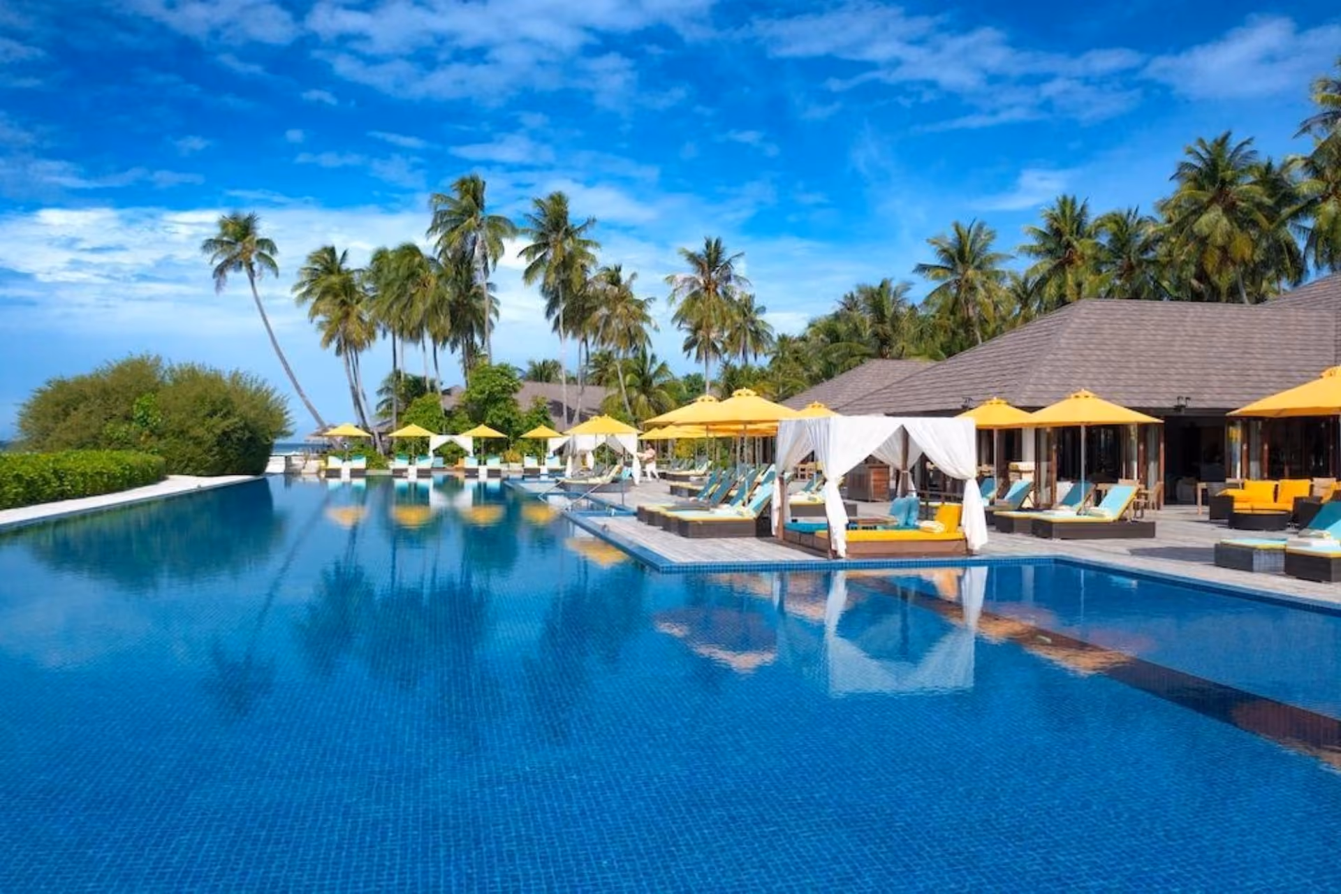Atmosphere Kanifushi resort pool with yellow umbrellas and palm trees