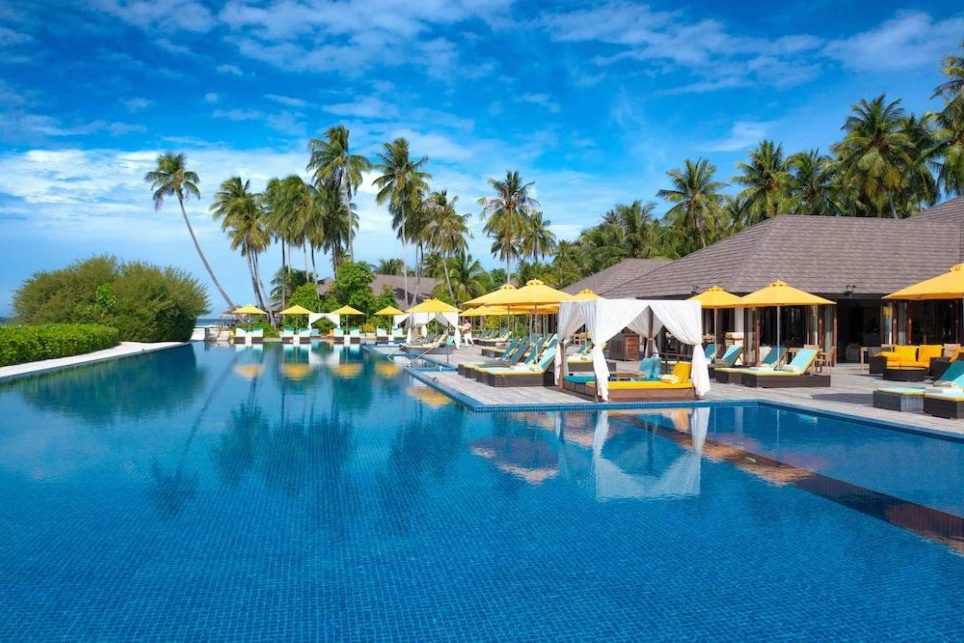 Atmosphere Kanifushi resort pool with yellow umbrellas and palm trees