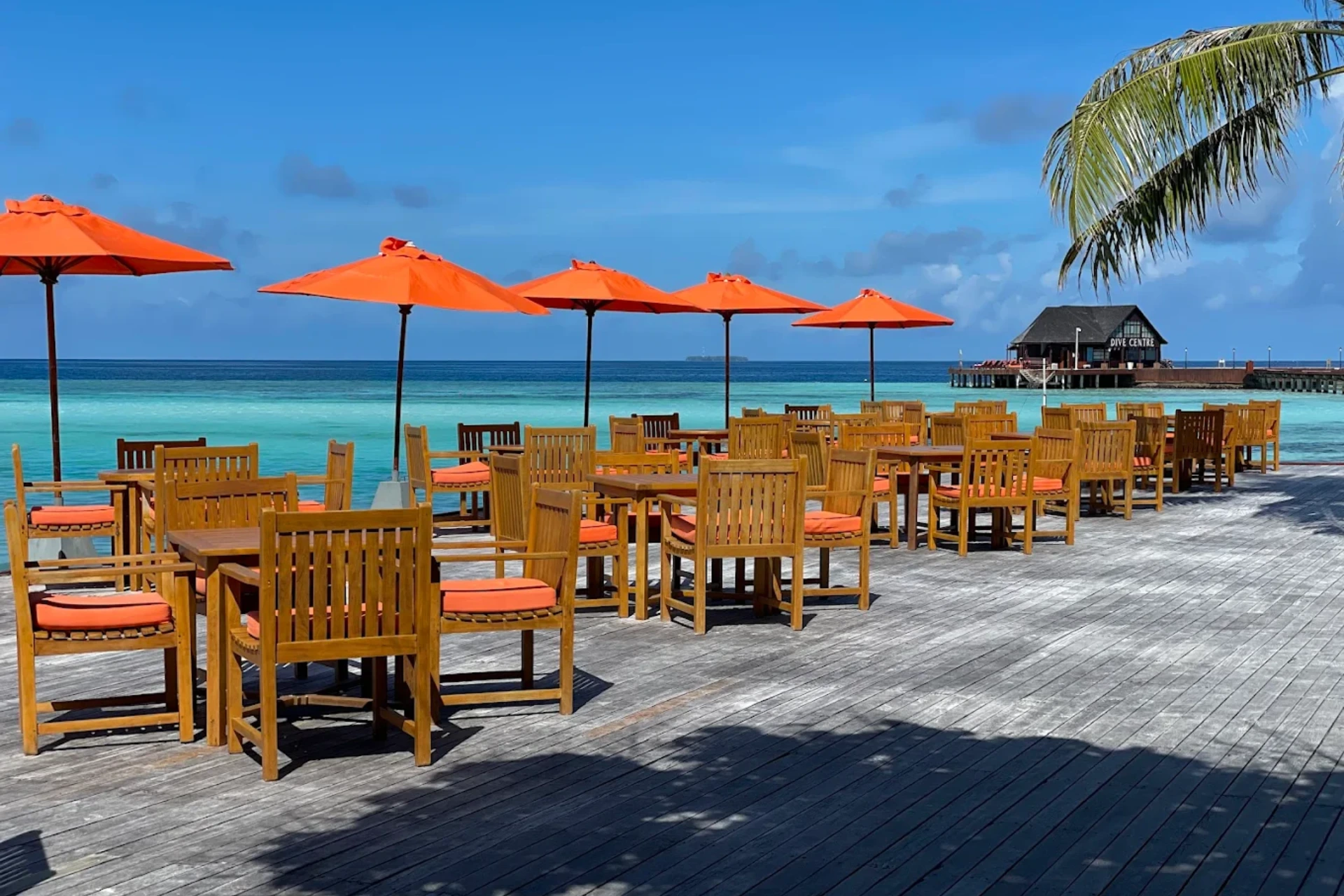 Sun Siyam Resort beach dining with orange umbrellas and wooden chairs