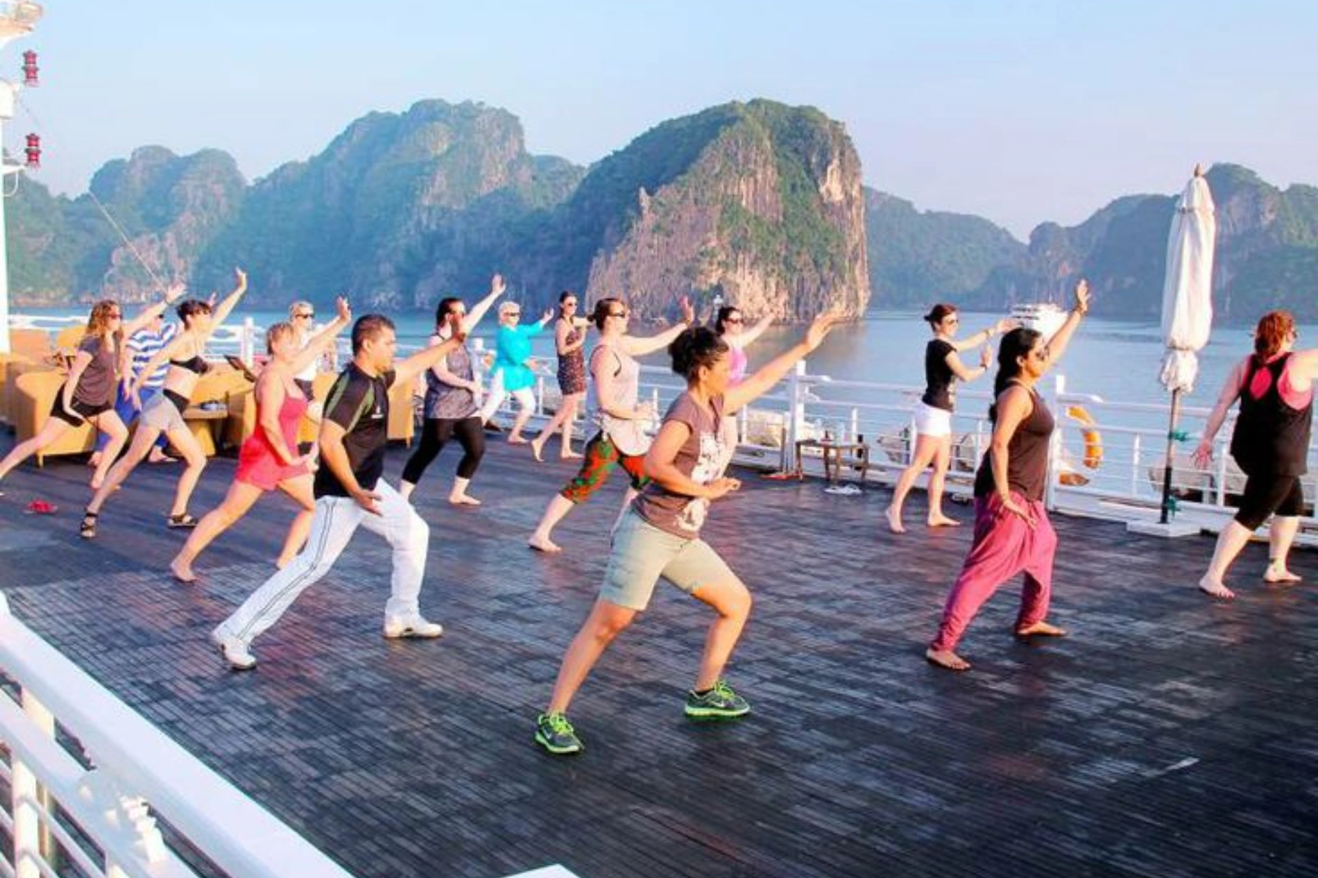 Group doing tai chi on boat deck near limestone islands