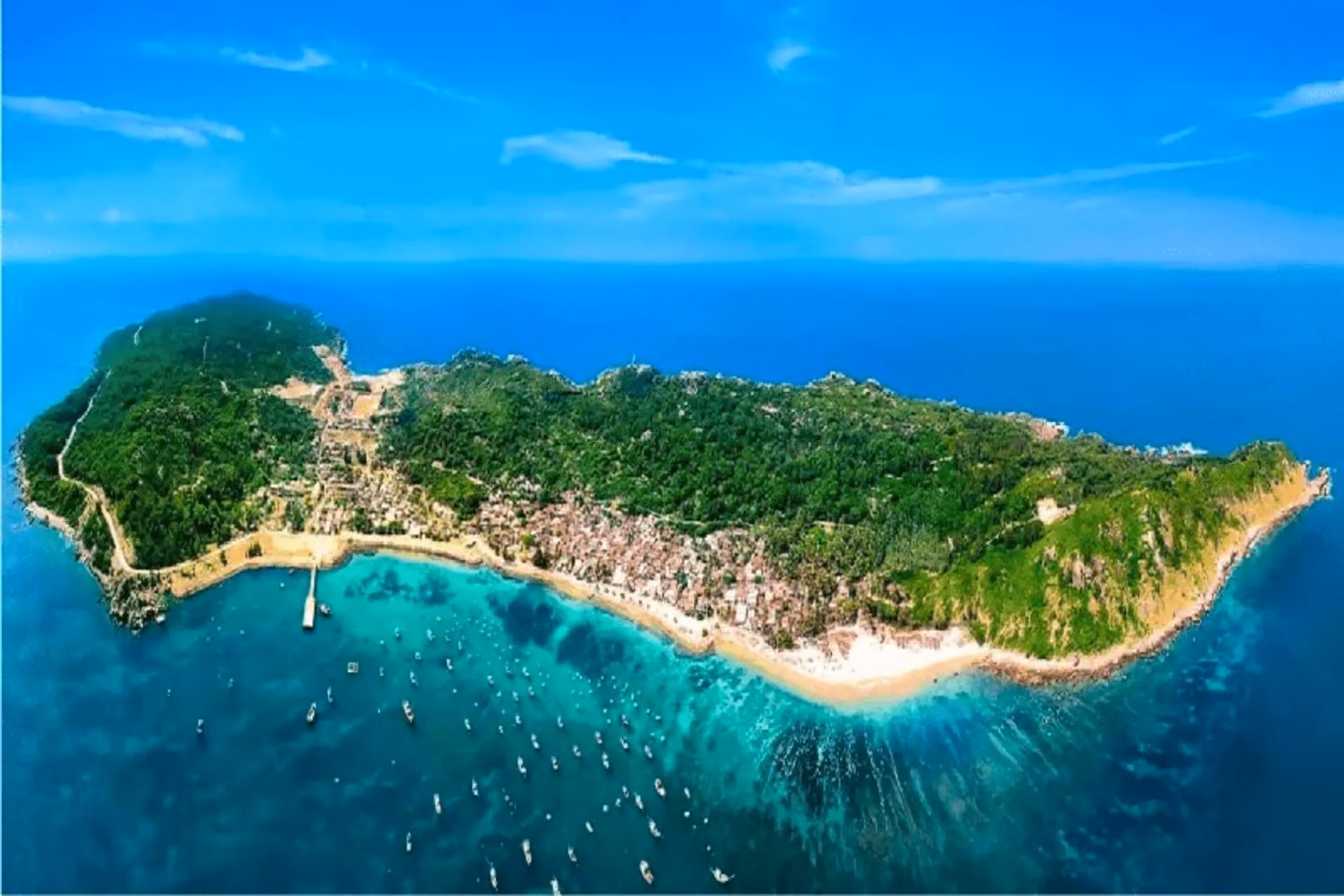 Cham Island beach with boats and green hills above