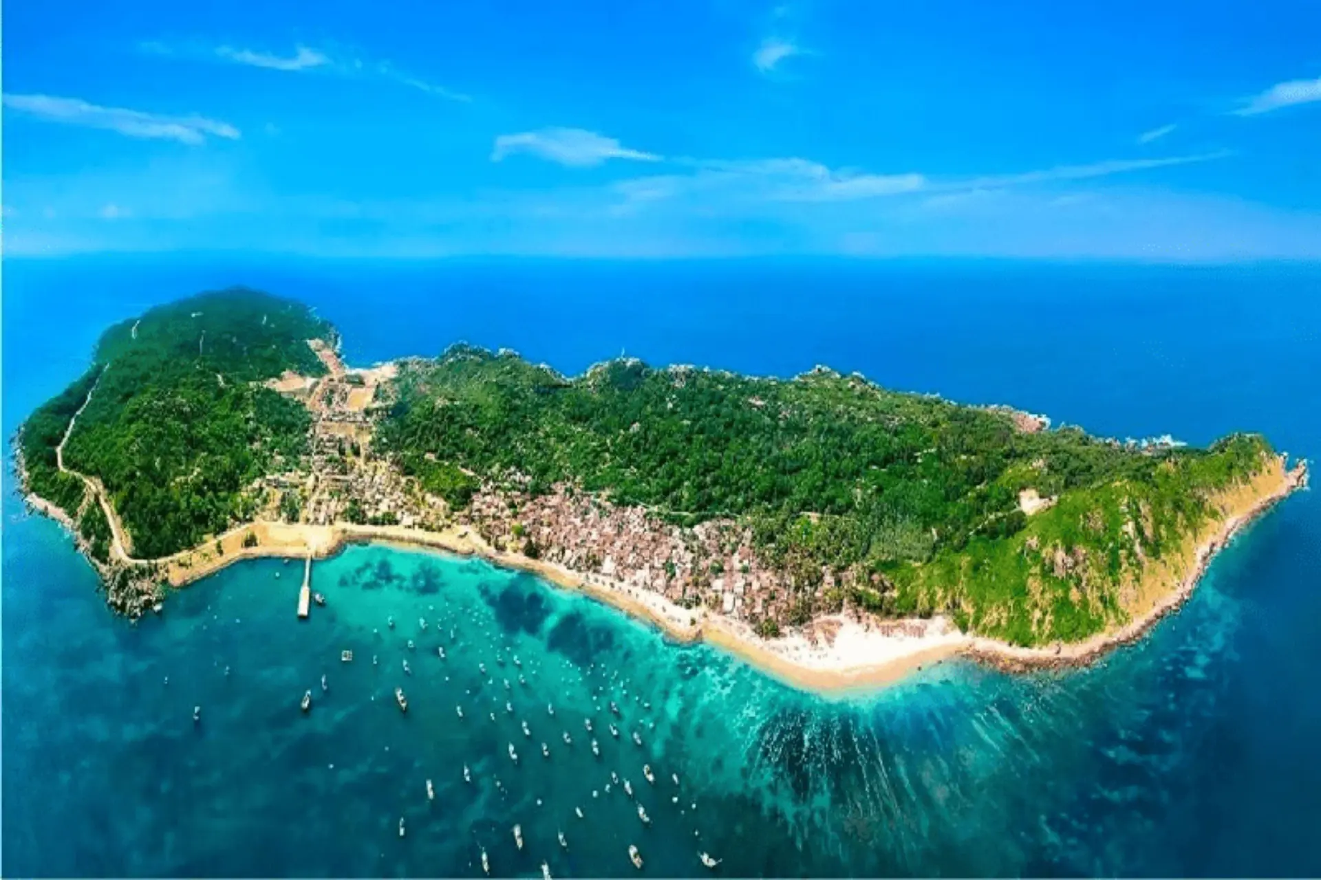 Cham Island beach with boats and green hills above