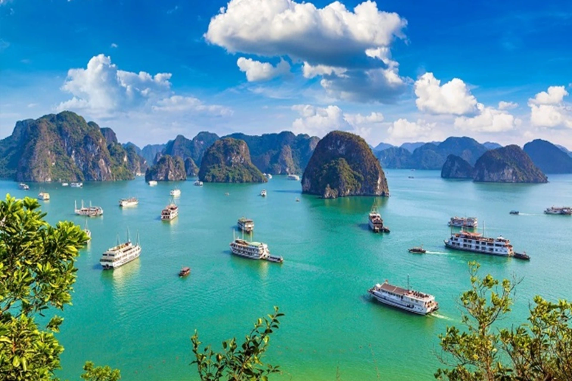 Boats floating on blue-green water among rocky islands at Halong Bay