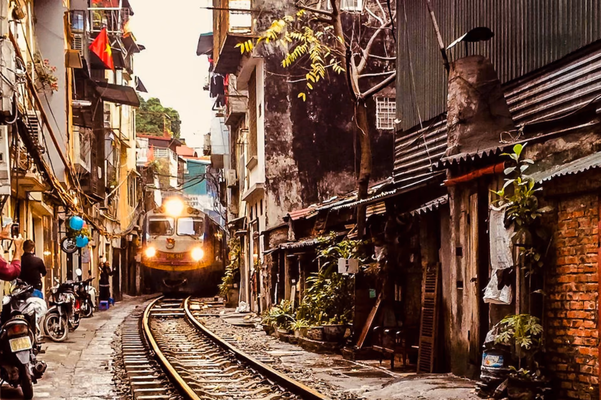 Train approaching through narrow Hanoi street with old buildings