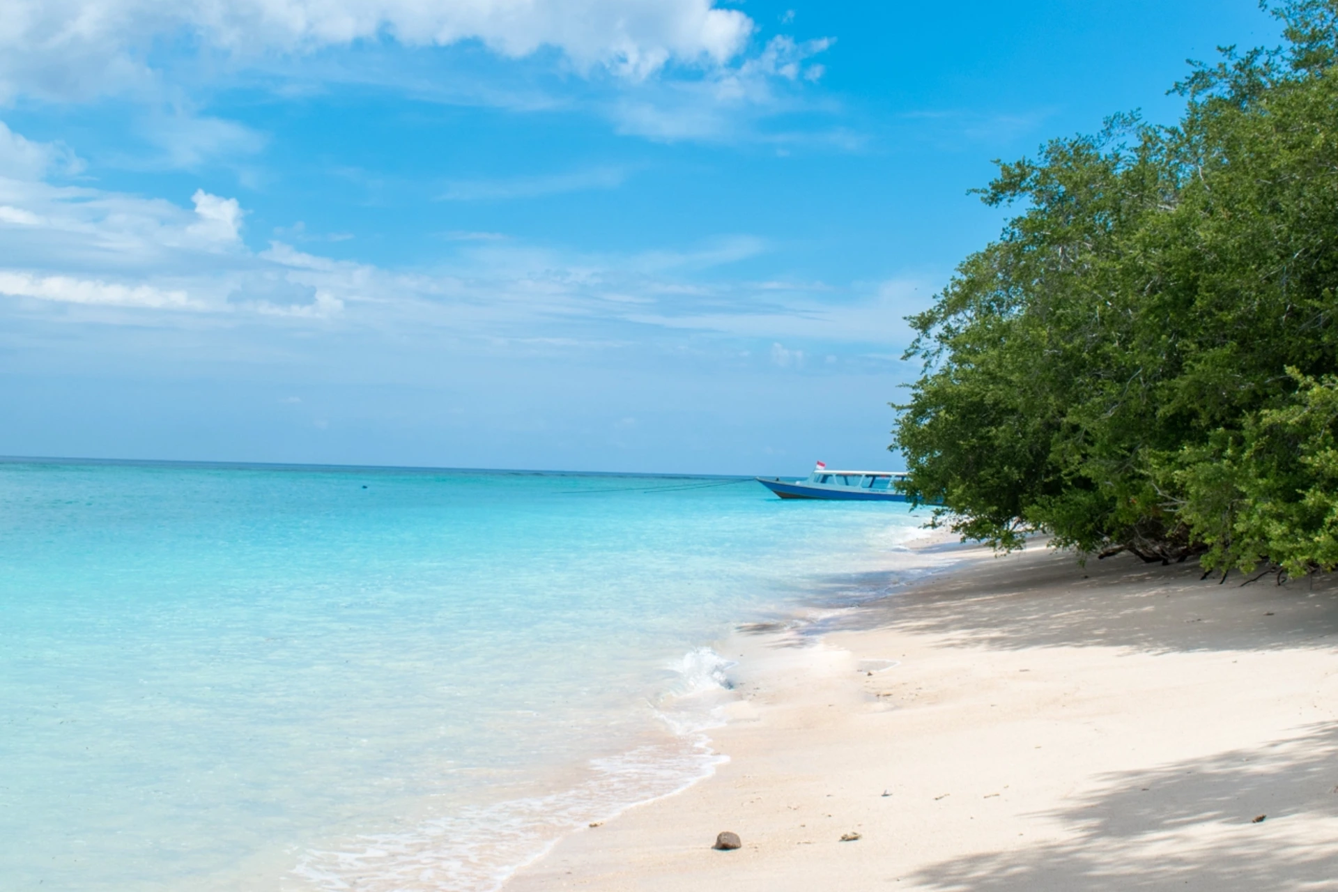 Gili White Sand beach with blue water and fishing boat