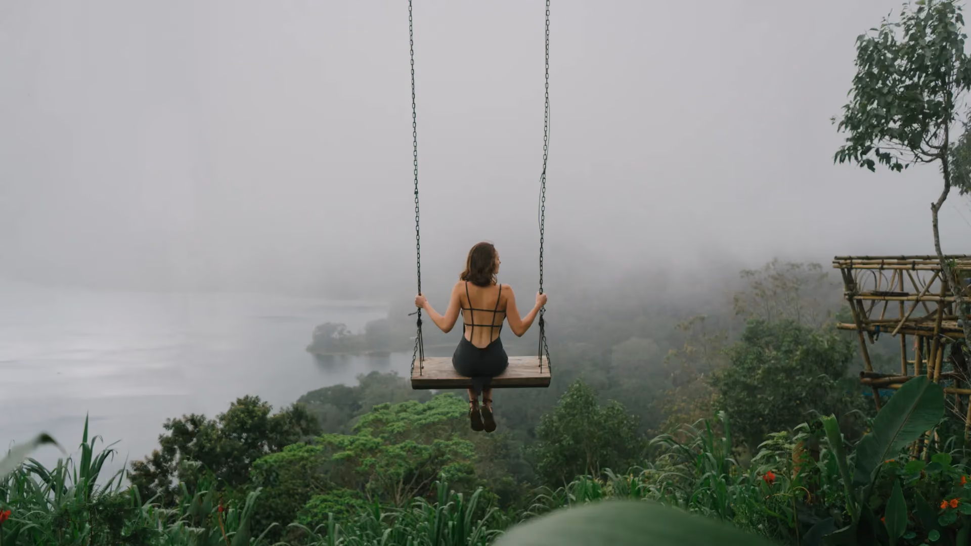 Woman on swing over misty river valley in Bali