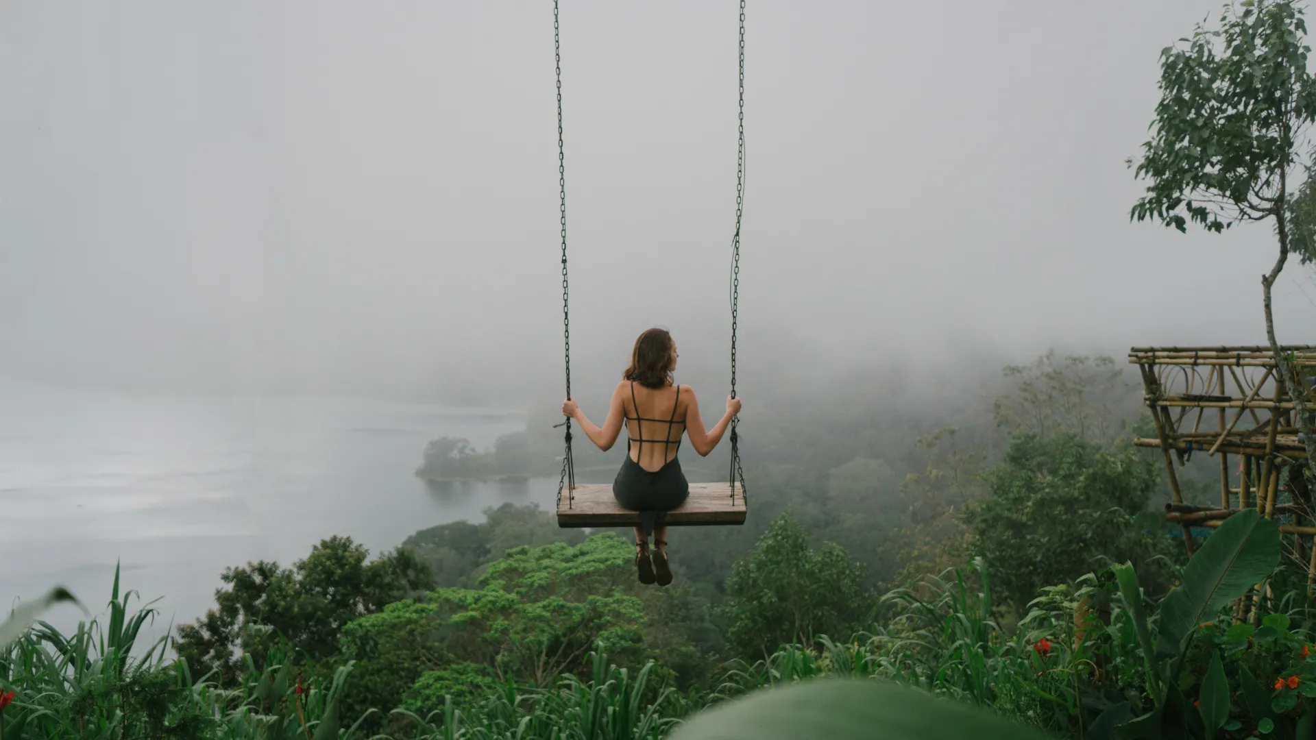 Woman on swing over misty river valley in Bali