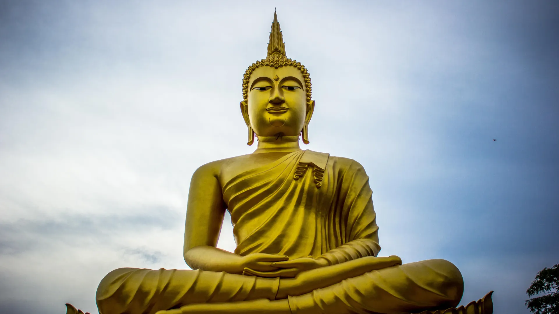 Golden Buddha statue sitting with hands raised to chest