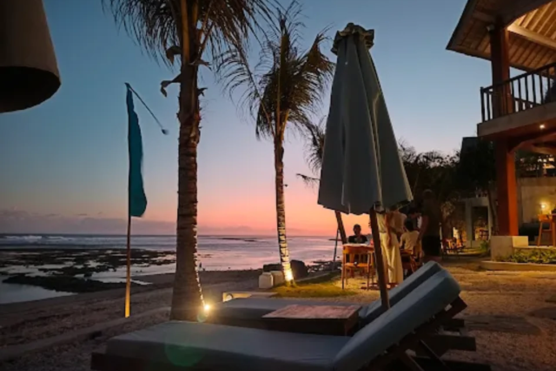 Beach at sunset with palm trees and umbrellas