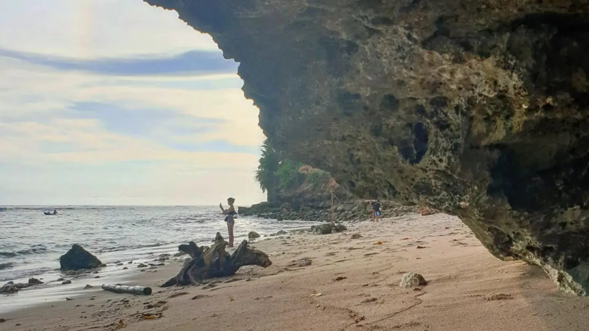 Pantai Batu Barak beach with tall rock cliff and swimmers