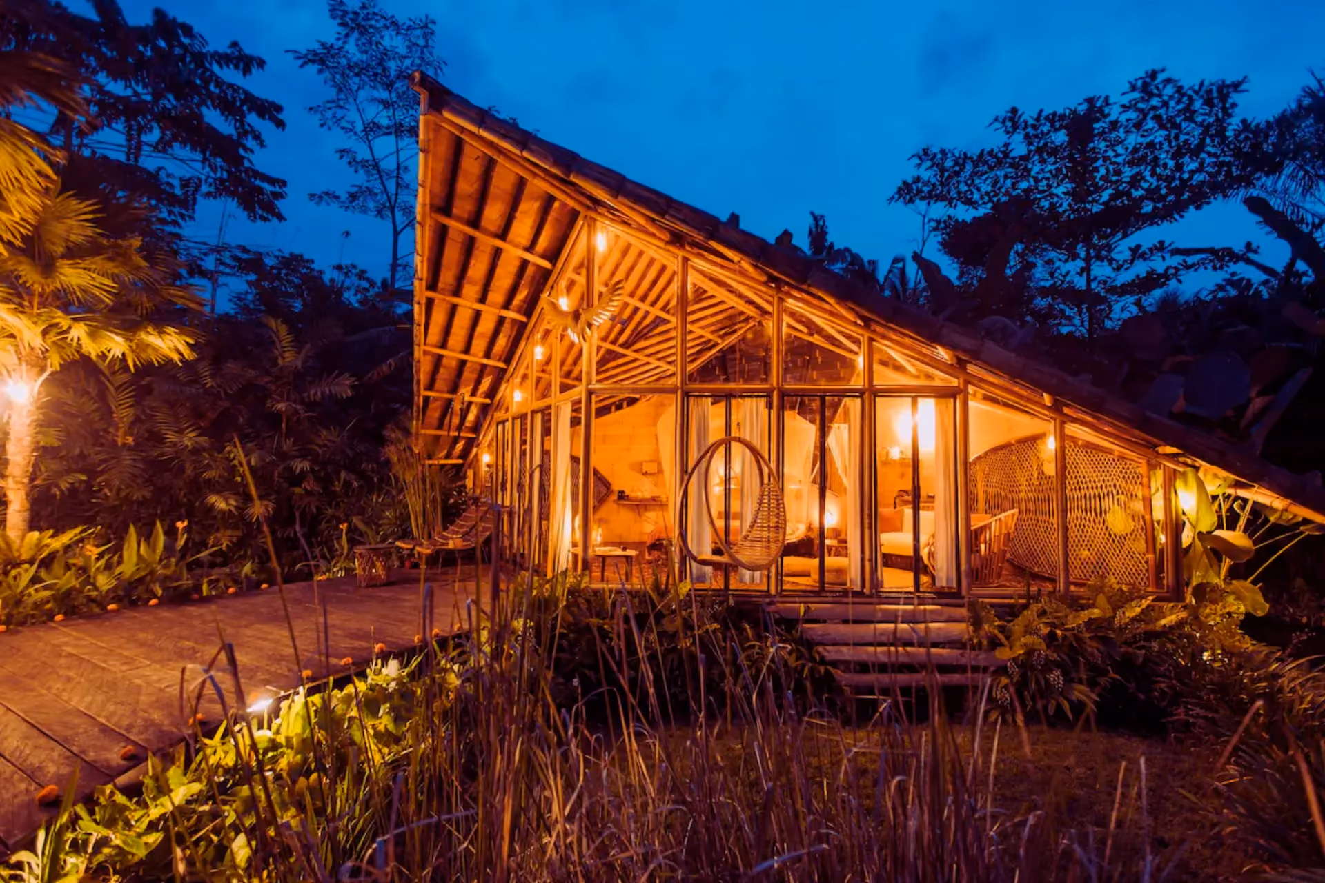 Glowing wooden tree house at night with hanging chair