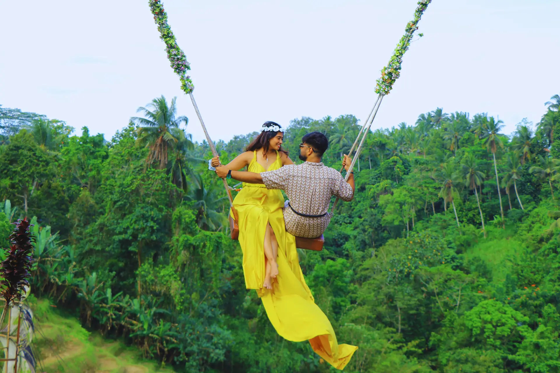Couple on jungle swing with green forest view