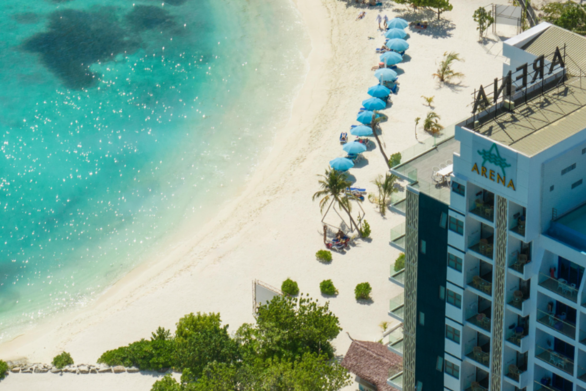 Arena Beach hotel with blue umbrellas along white sand