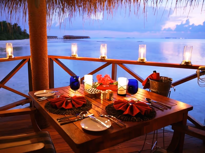 Outdoor dinner table set by the ocean at dusk