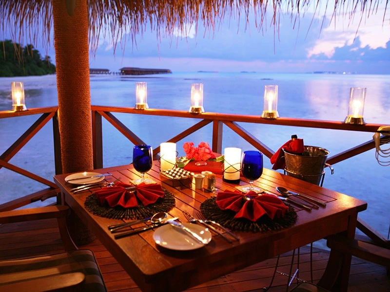 Outdoor dinner table set by the ocean at dusk