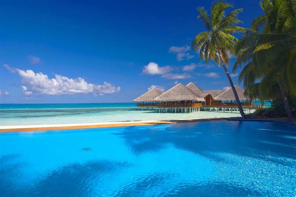 Medhufushi Pool and Bar with thatched roof buildings over blue water