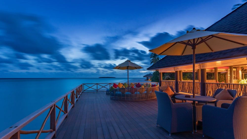 Seaside deck with umbrellas and seating at dusk