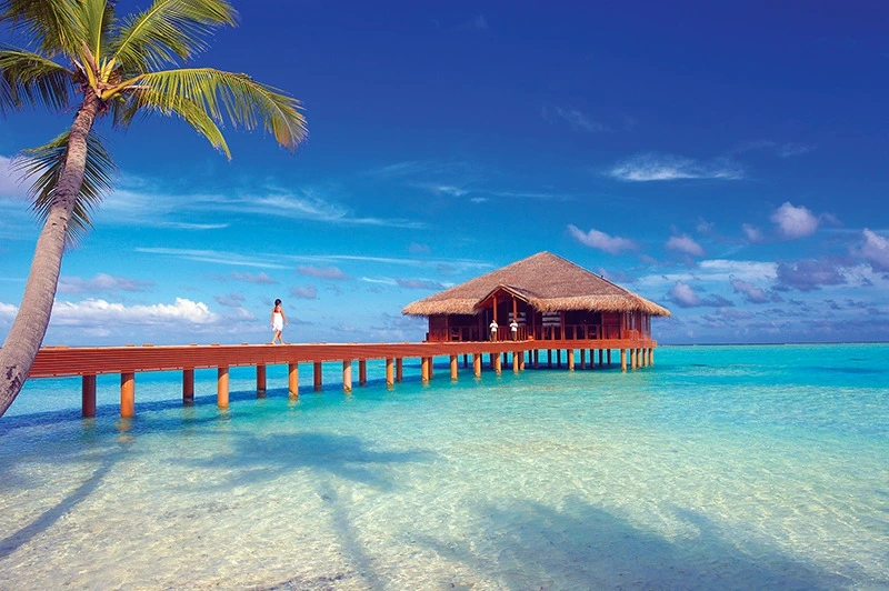Wooden pier leading to thatched-roof spa building at Medhufushi