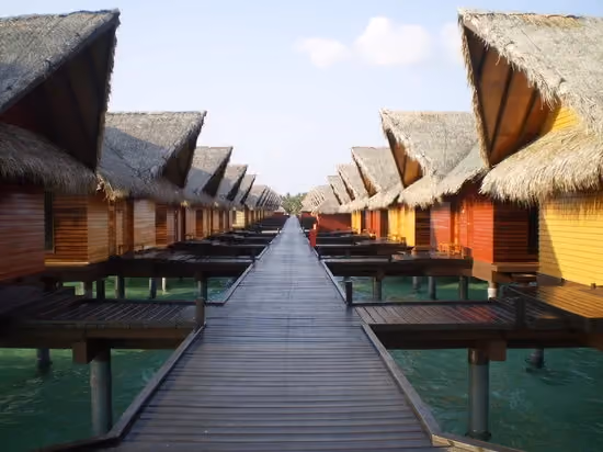 Row of wooden bungalows with straw roofs over water
