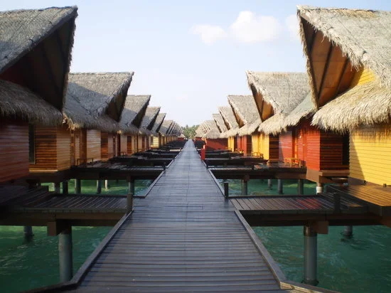 Row of wooden bungalows with straw roofs over water