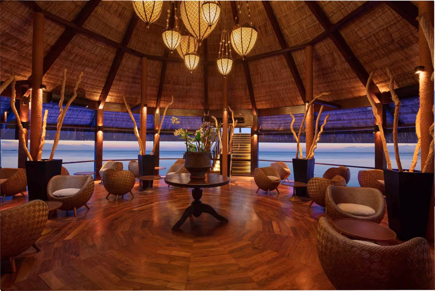 Kandholi Bar round room with woven chairs and ocean view at dusk