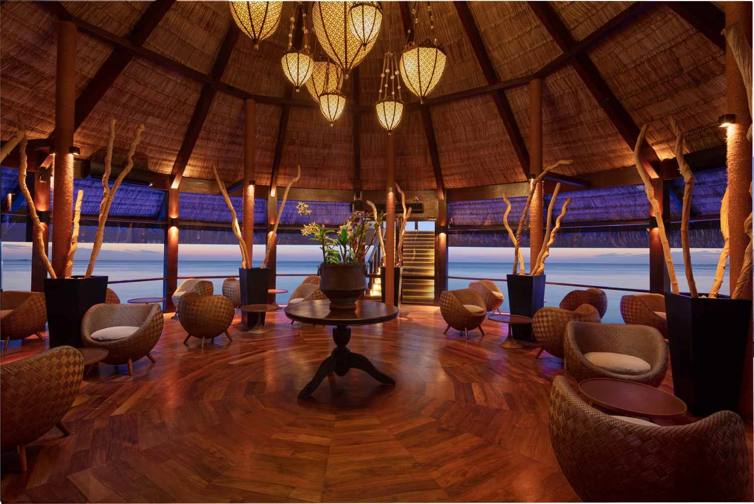 Kandholi Bar round room with woven chairs and ocean view at dusk