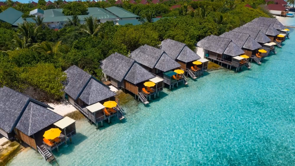 Row of thatched bungalows over clear blue-green water