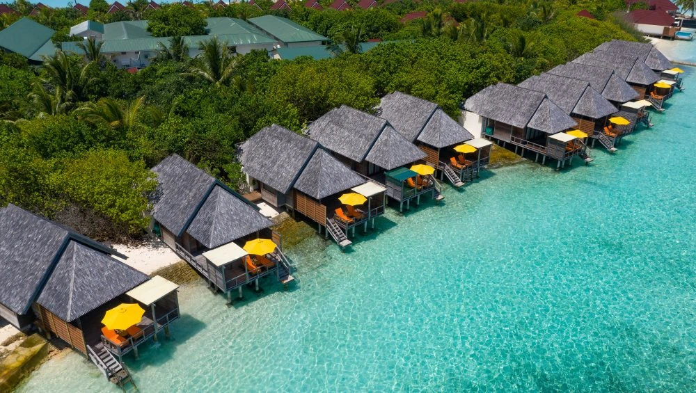 Row of thatched bungalows over clear blue-green water