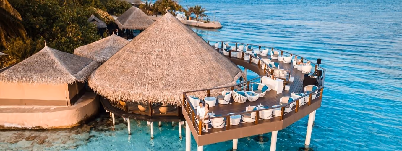 Kandholi Sky Bar with thatched roof over clear blue water