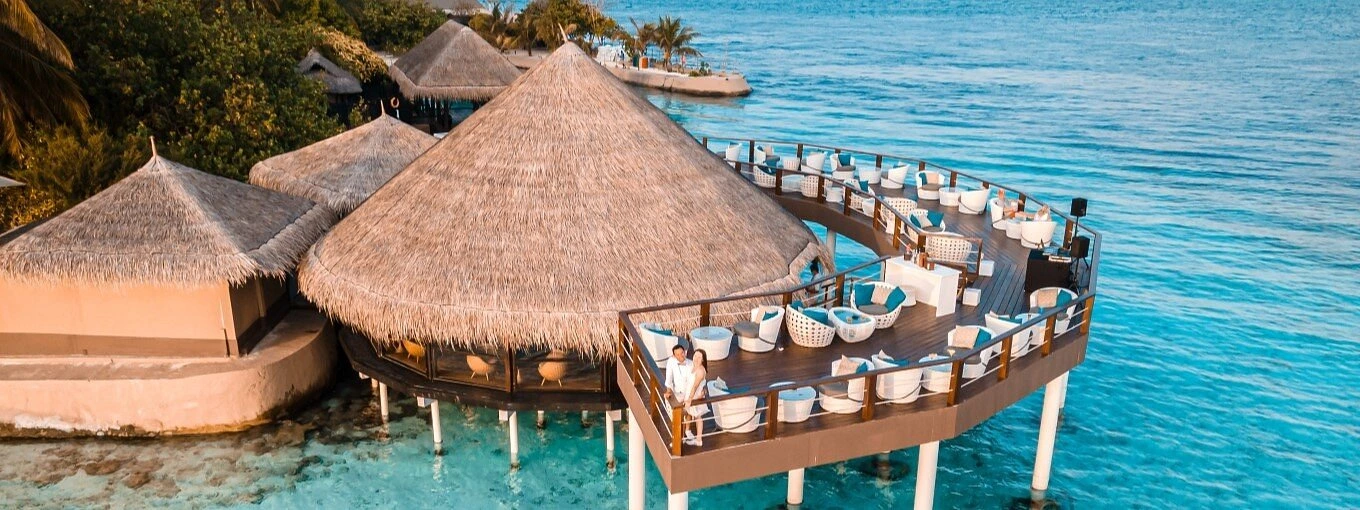 Kandholi Sky Bar with thatched roof over clear blue water
