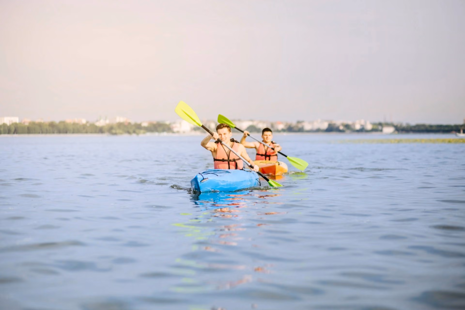 Two men kayaking in open water with life jackets and paddles – water activities in New Zealand vs Switzerland