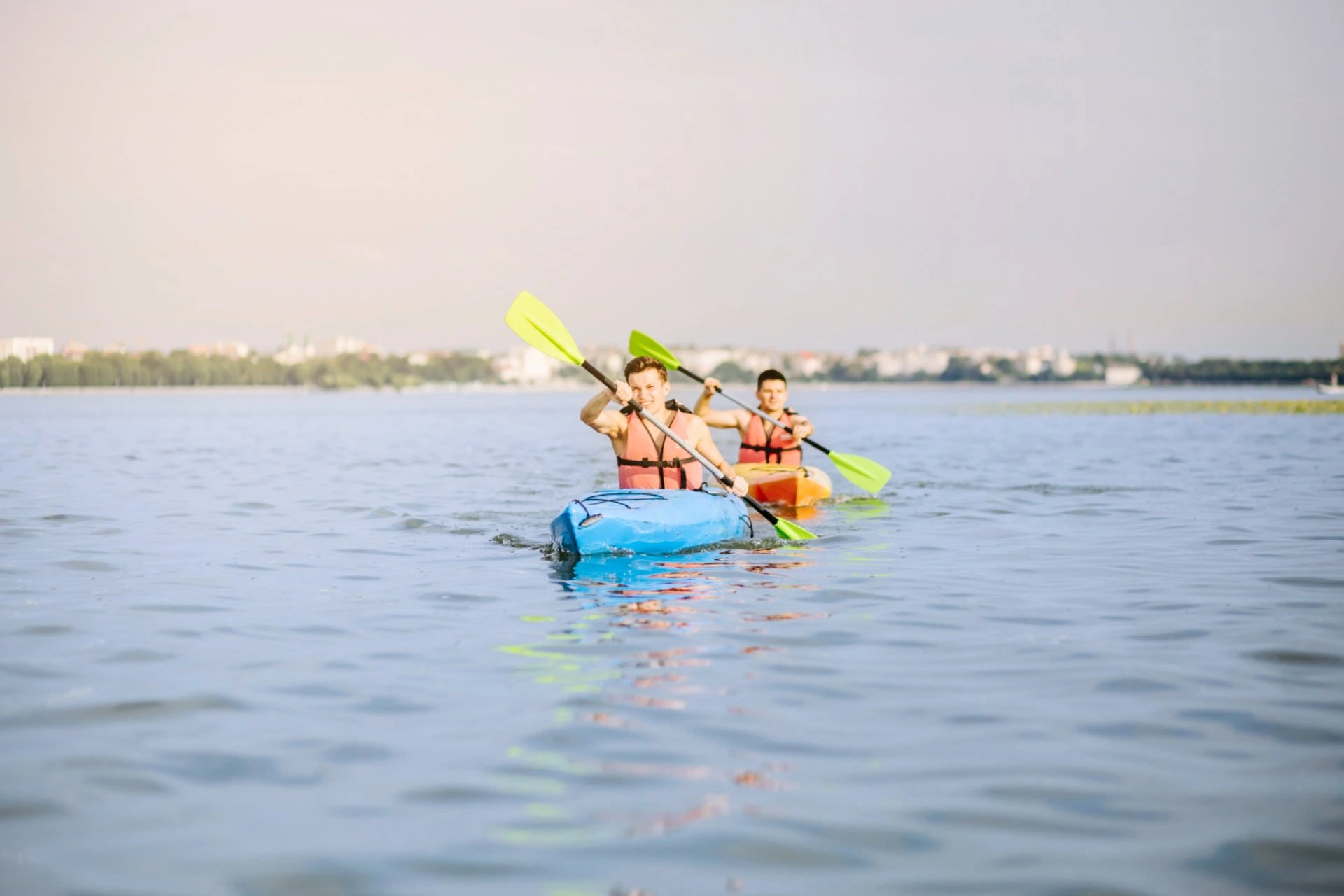 Two men kayaking in open water with life jackets and paddles – water activities in New Zealand vs Switzerland