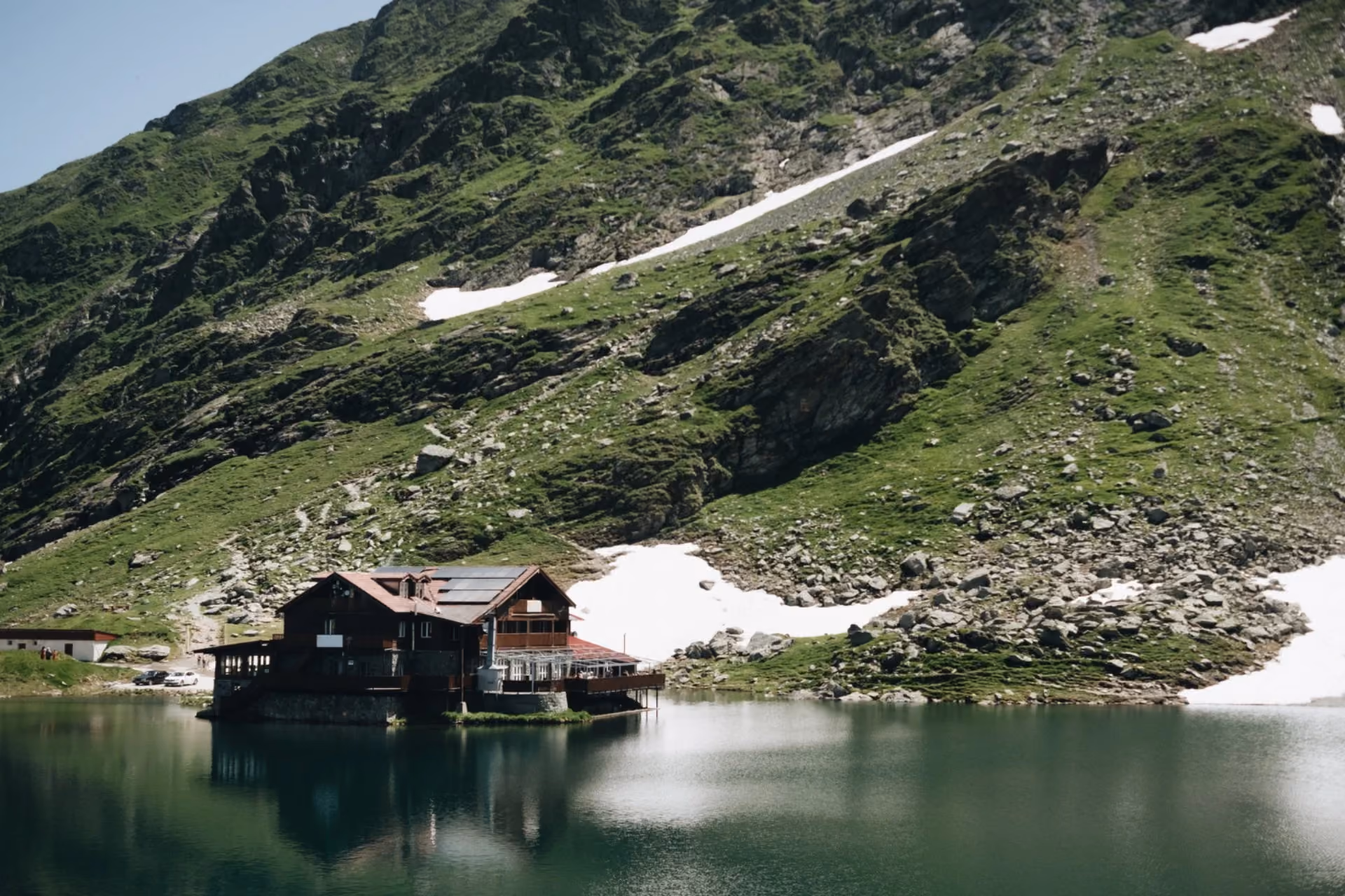 Alpine lakeside lodge with mountain reflection – New Zealand vs Switzerland accommodation