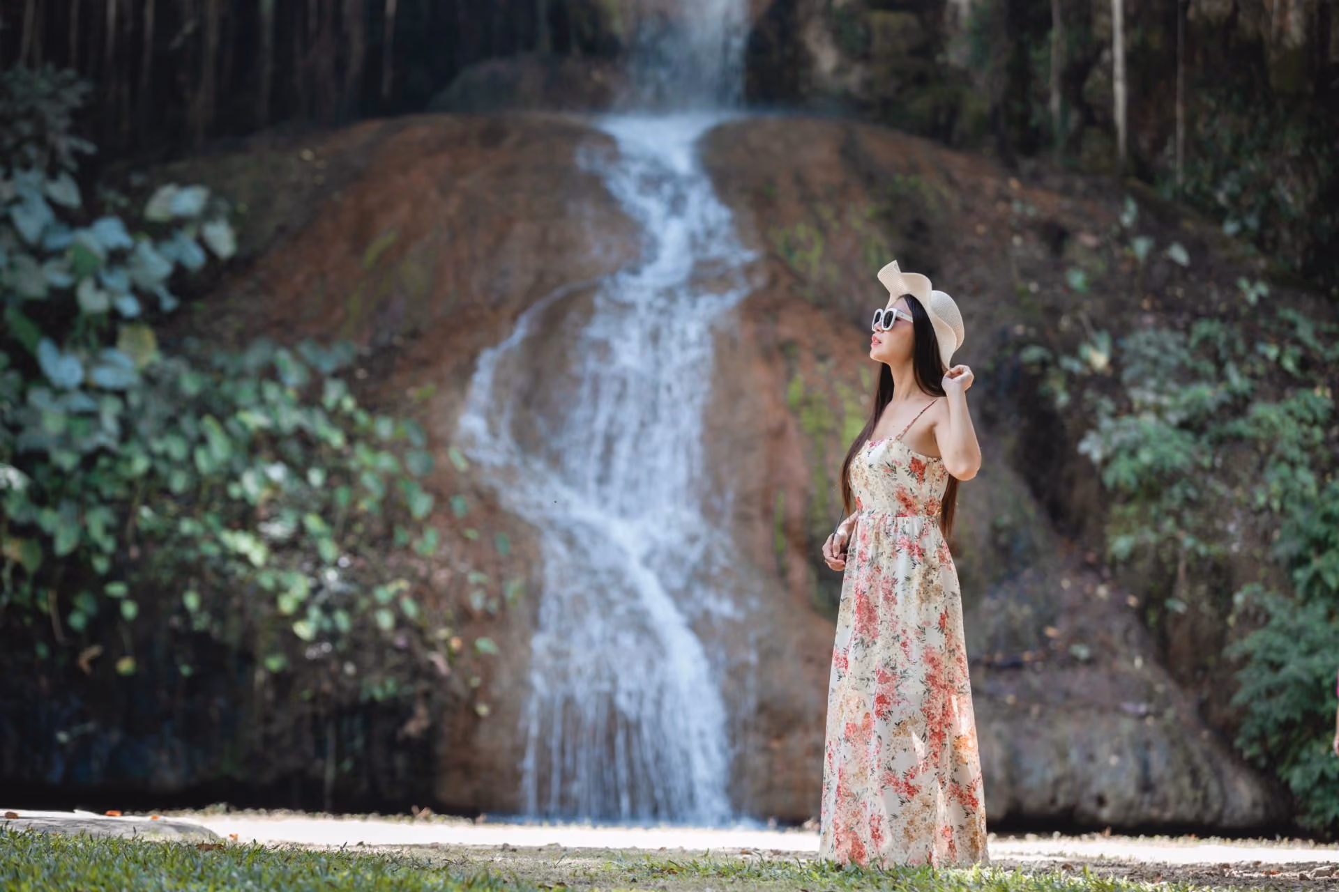 Woman standing near a waterfall in Ella surrounded by lush greenery and scenic nature