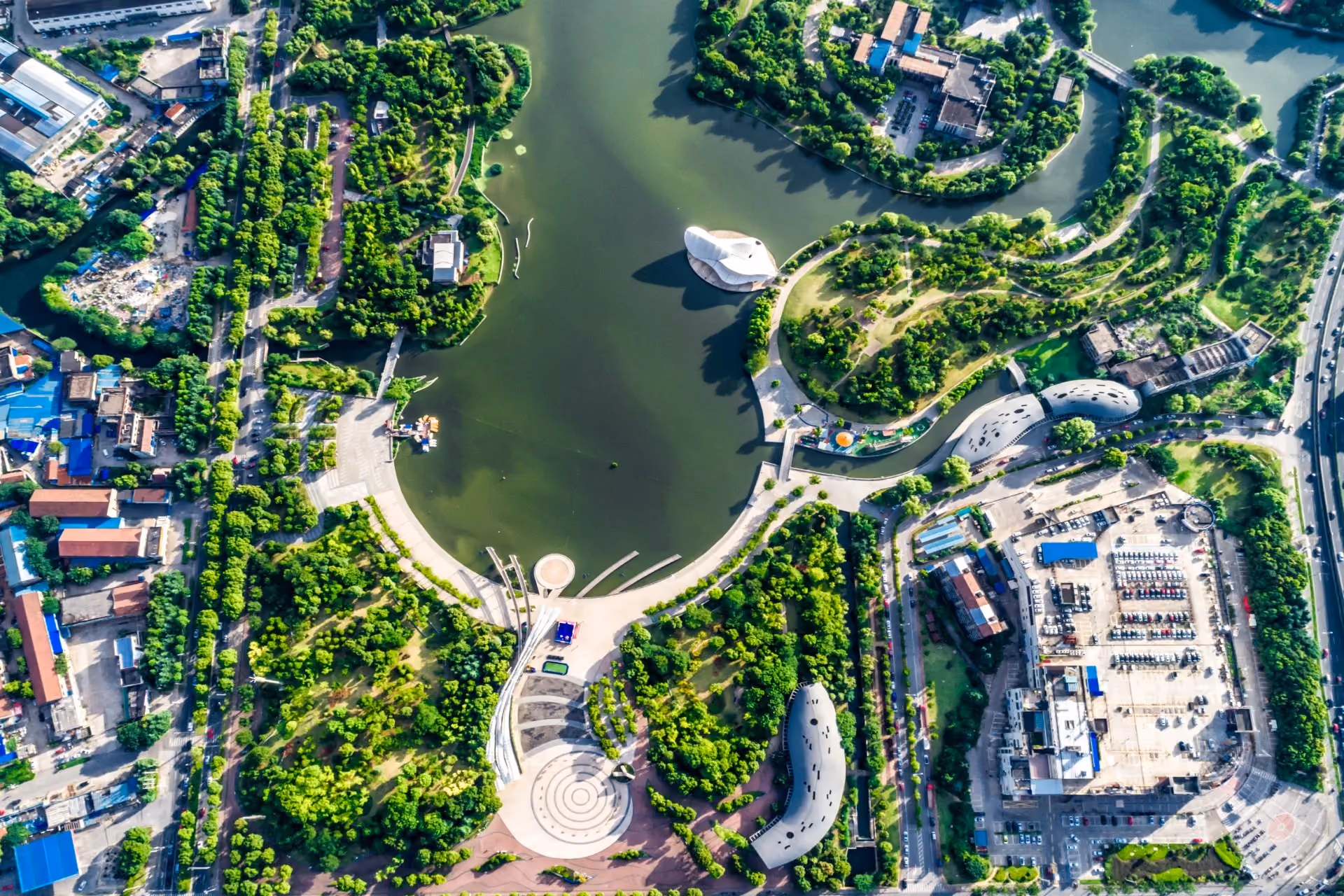 Aerial view of a lush green urban park and lake in Malaysia surrounded by modern city buildings and winding pathways