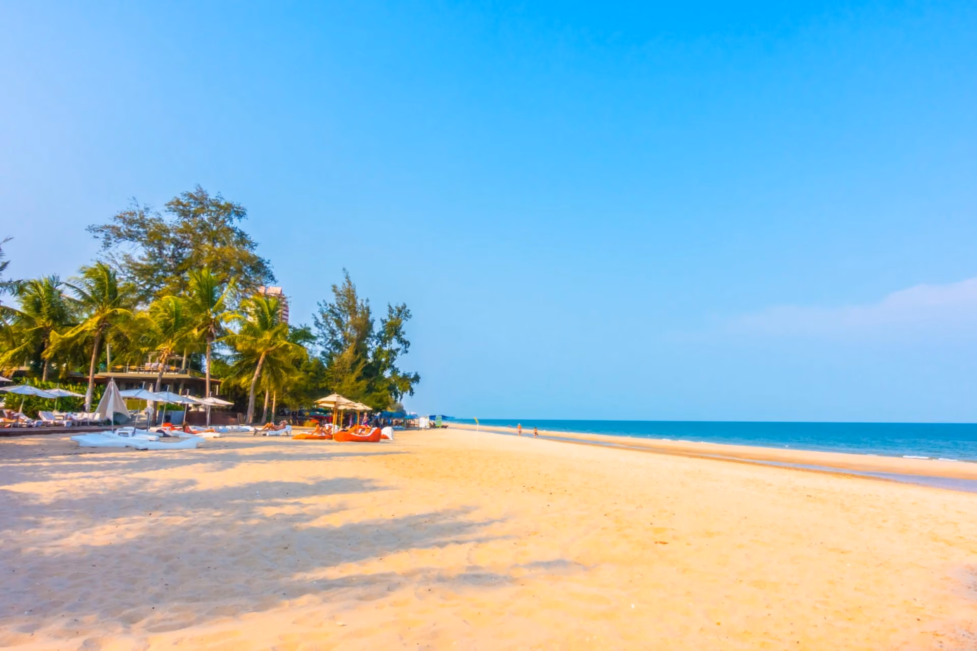 Sunny Kuta Beach with palm trees, soft white sand, and calm blue sea