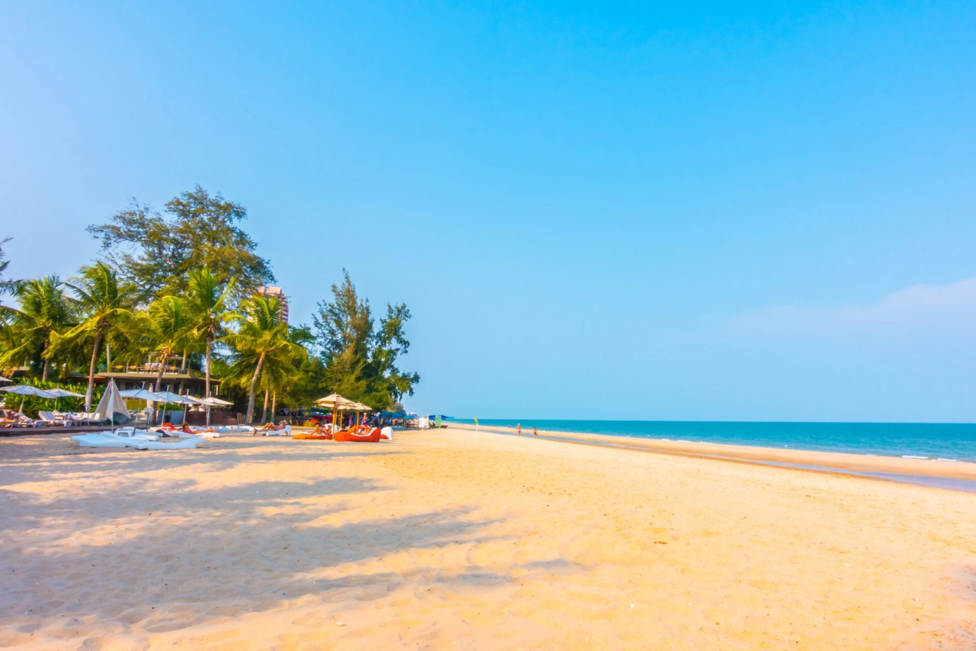 Sunny Kuta Beach with palm trees, soft white sand, and calm blue sea