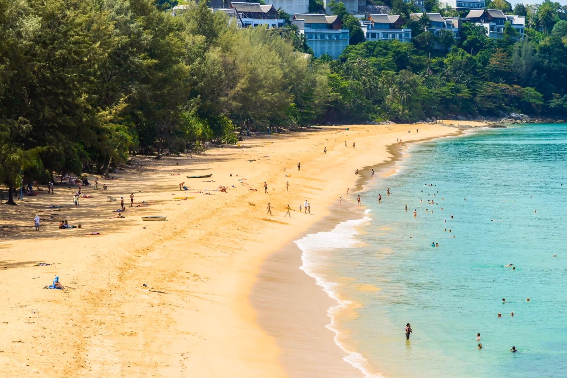 Scenic sandy beach in Vietnam with turquoise waters, lush greenery, and people enjoying the shoreline in May.