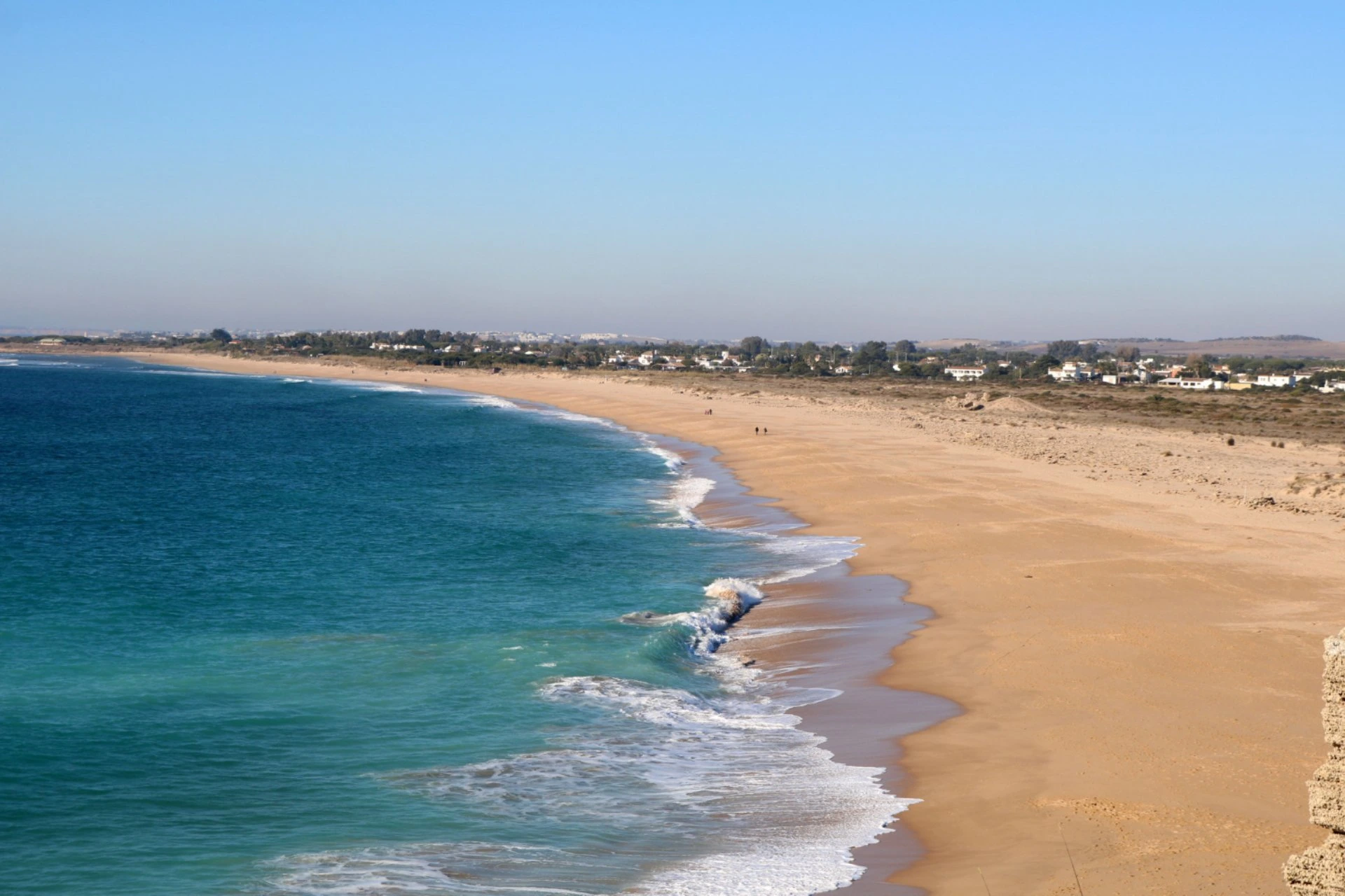 Peaceful sandy beach coastline in Oman with turquoise waters and clear blue sky