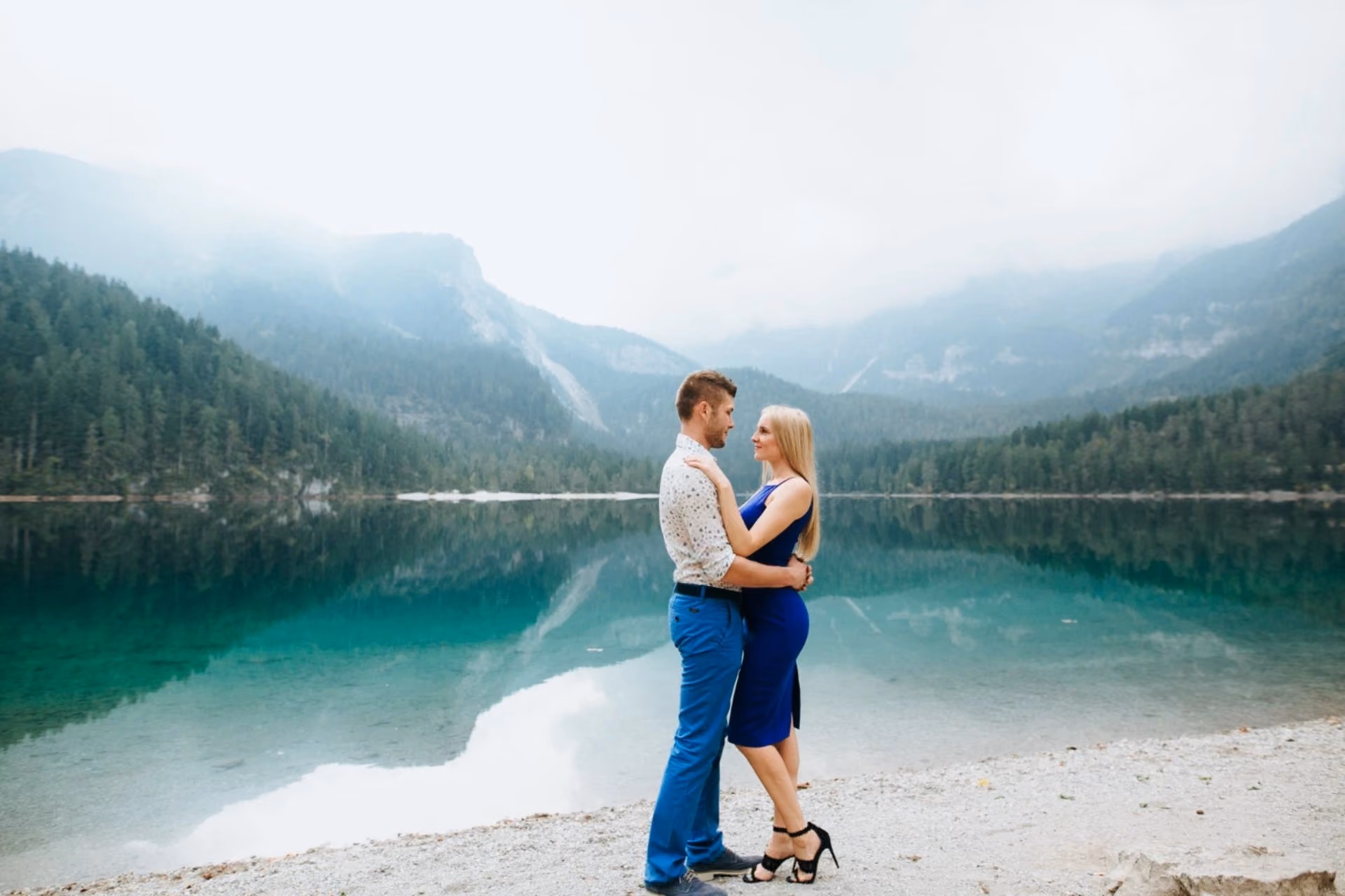Couple enjoying a romantic lakeside moment in Finland surrounded by forests and mountains