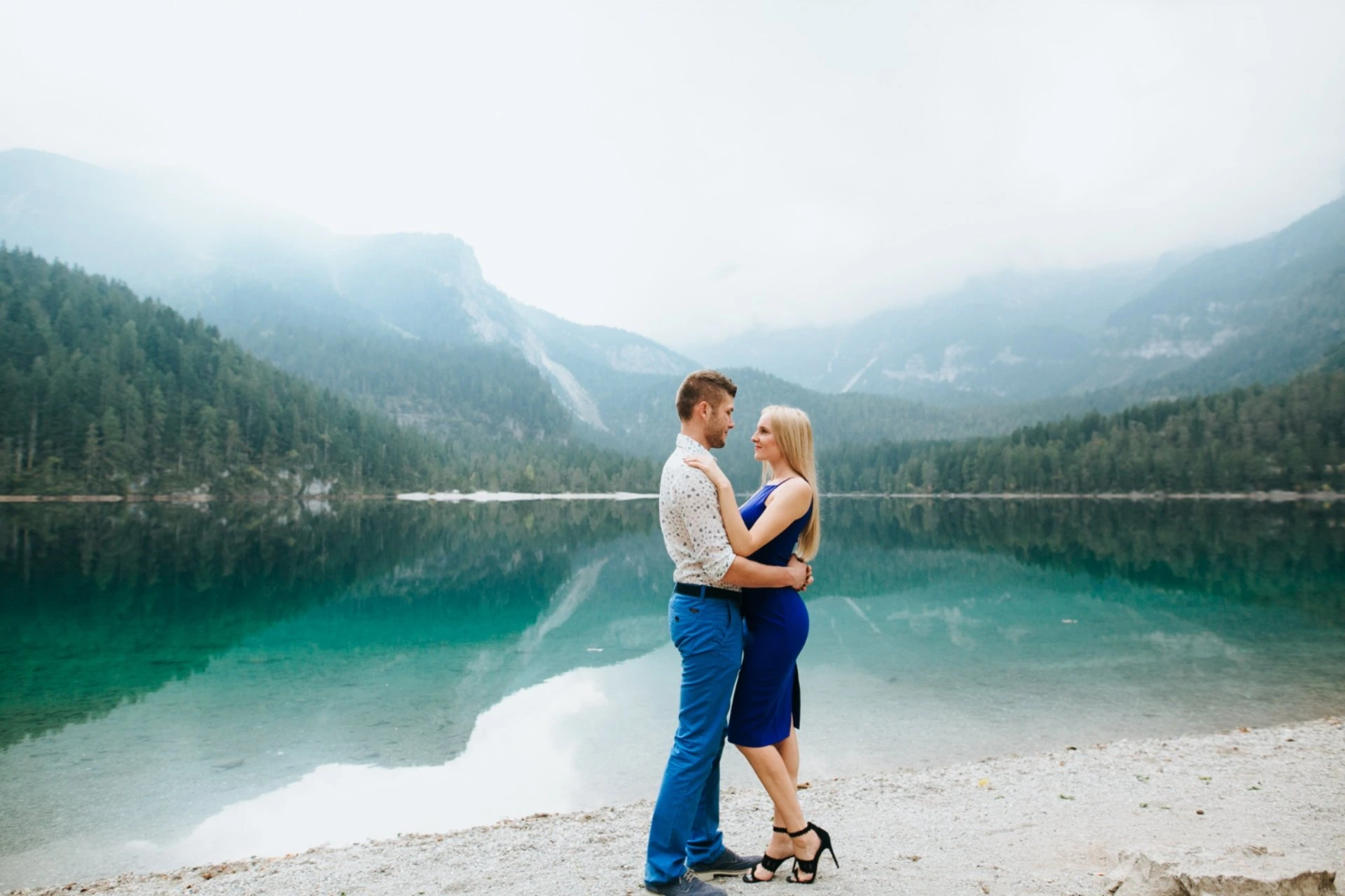 Couple enjoying a romantic lakeside moment in Finland surrounded by forests and mountains