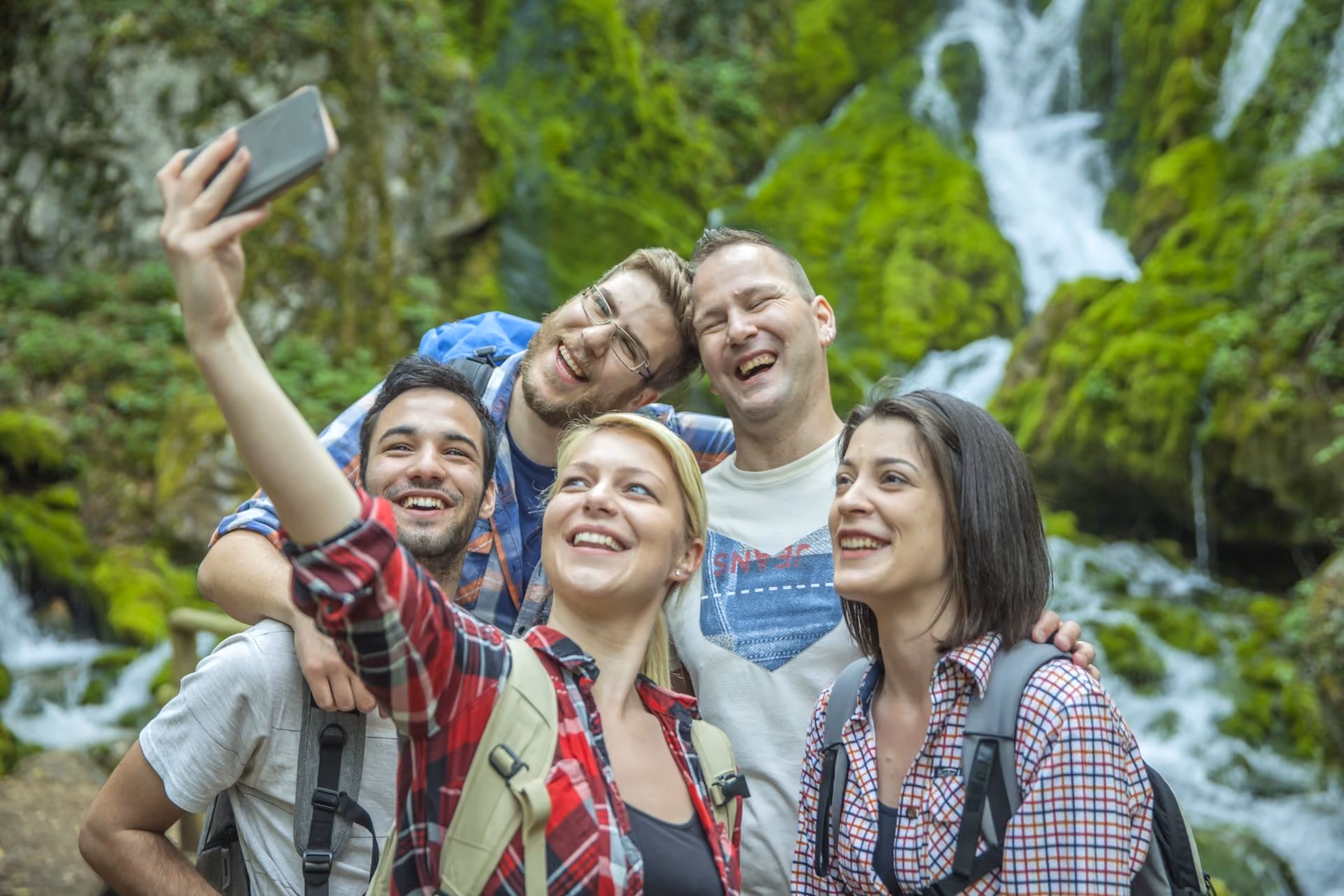 Travellers exploring a scenic waterfall in New Zealand during October, highlighting the relaxed tourist experience in New Zealand vs Switzerland in October