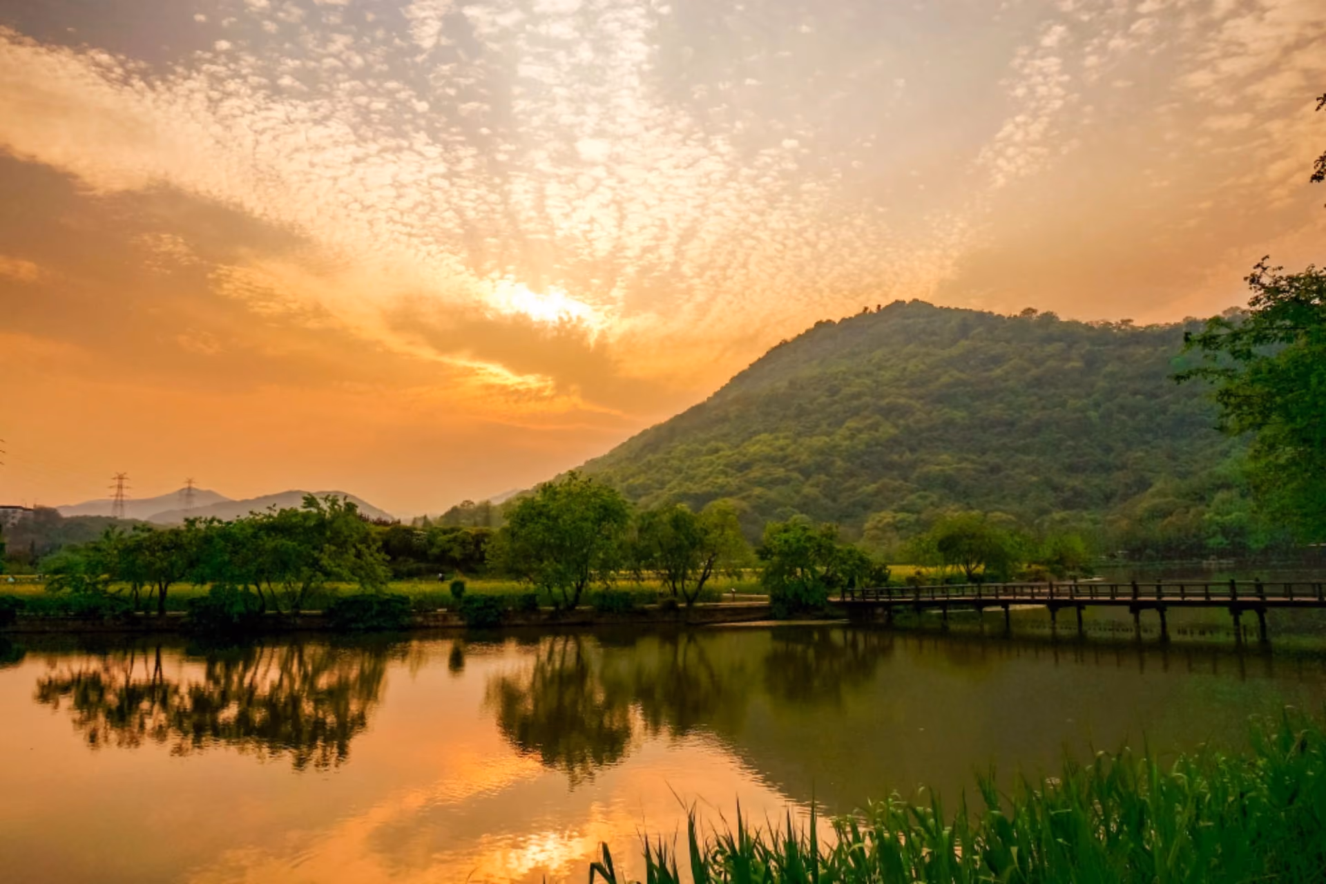 Golden sunset over a calm lake and green hill.