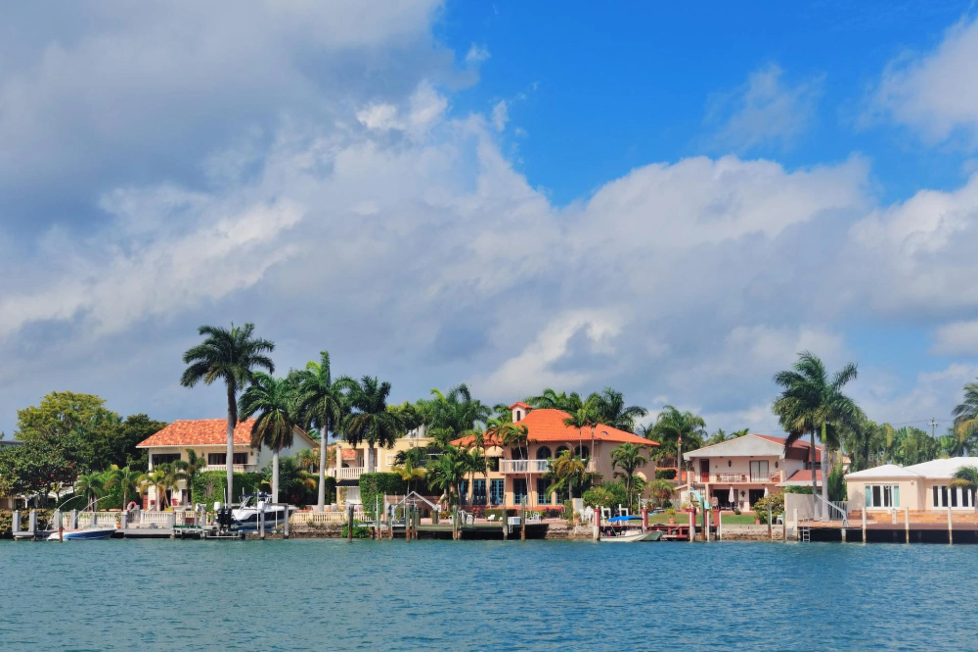 Waterfront homes lined with palm trees along the coast in Mauritius under clear blue skies during October.