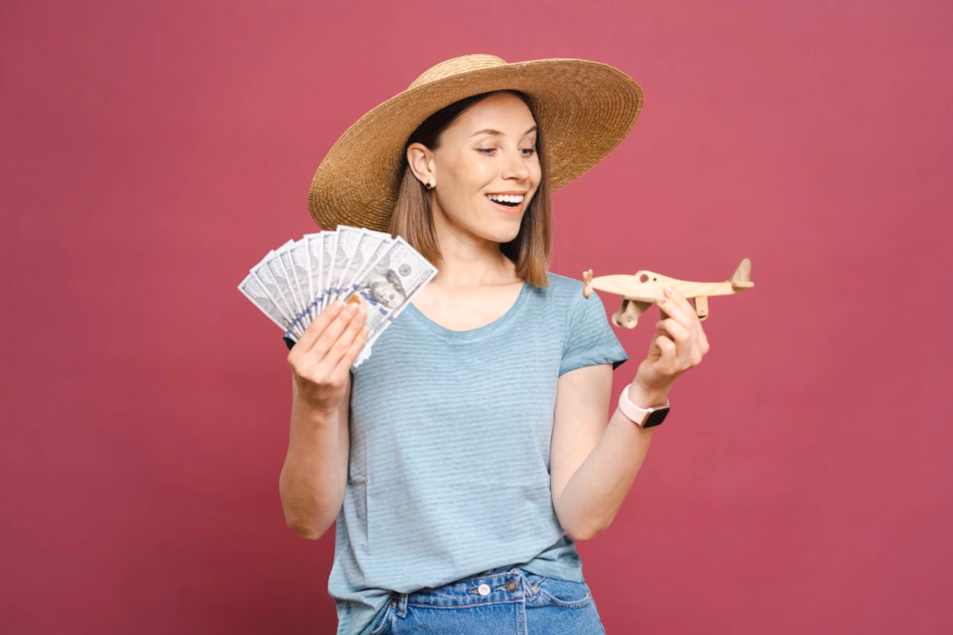 Traveller holding cash and a toy airplane, representing the budget comparison between Bali and Vietnam for travel in October.
