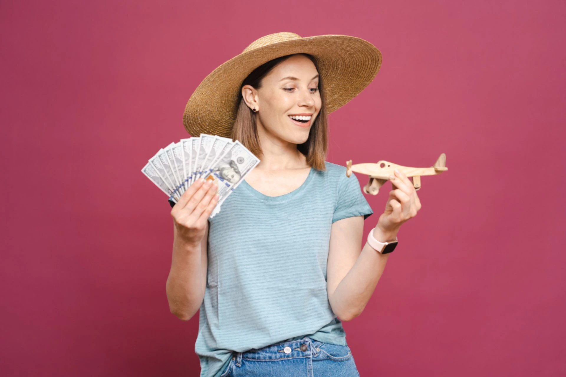 Traveller holding cash and a toy airplane, representing the budget comparison between Bali and Vietnam for travel in October.