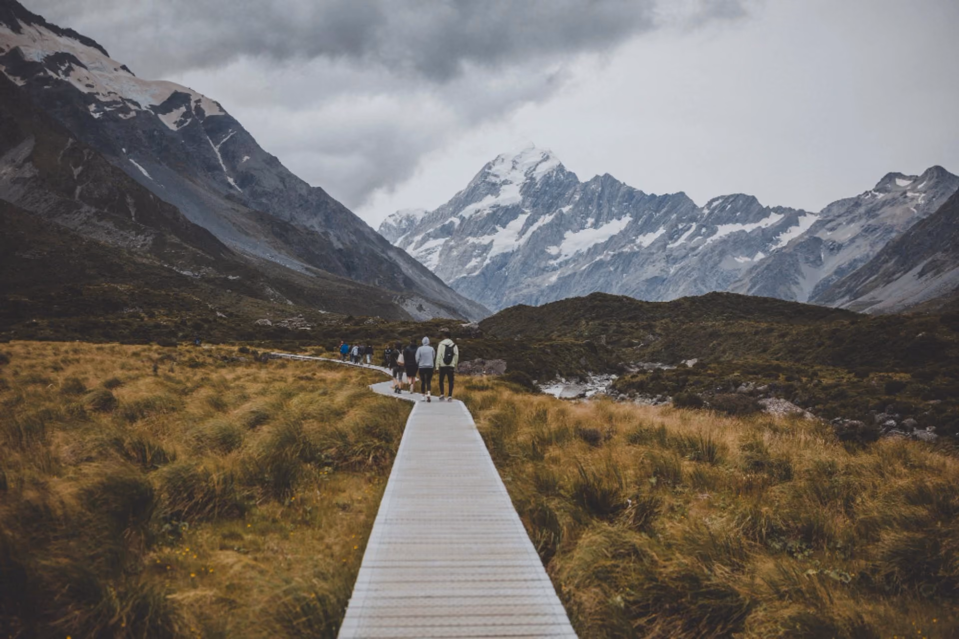Hikers walking through New Zealand's spring mountain landscape in October, ideal for travellers comparing New Zealand vs Switzerland in October