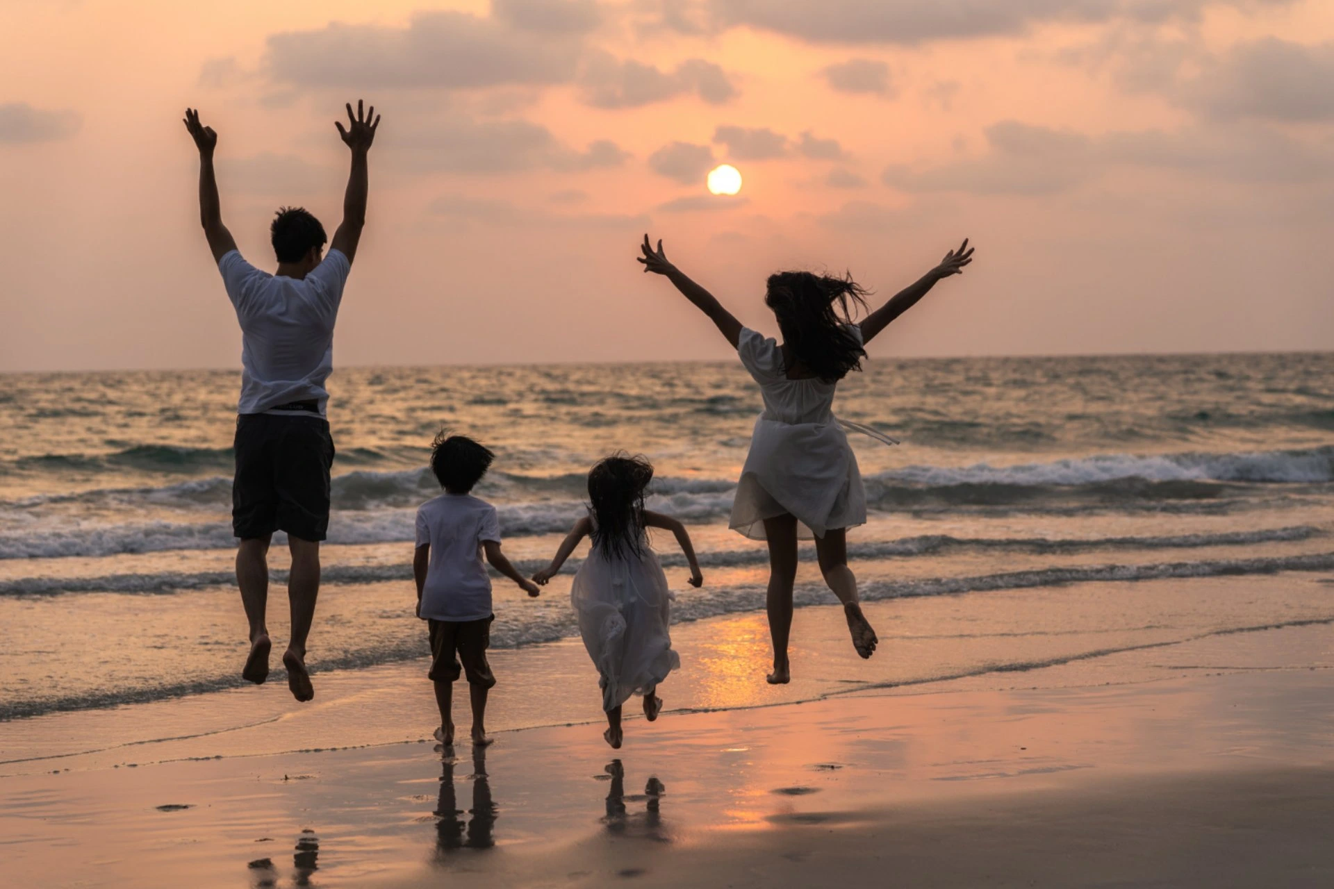 Family enjoying a sunset beach vacation, comparing Bali vs Thailand for family travel with kid-friendly beaches and resorts.