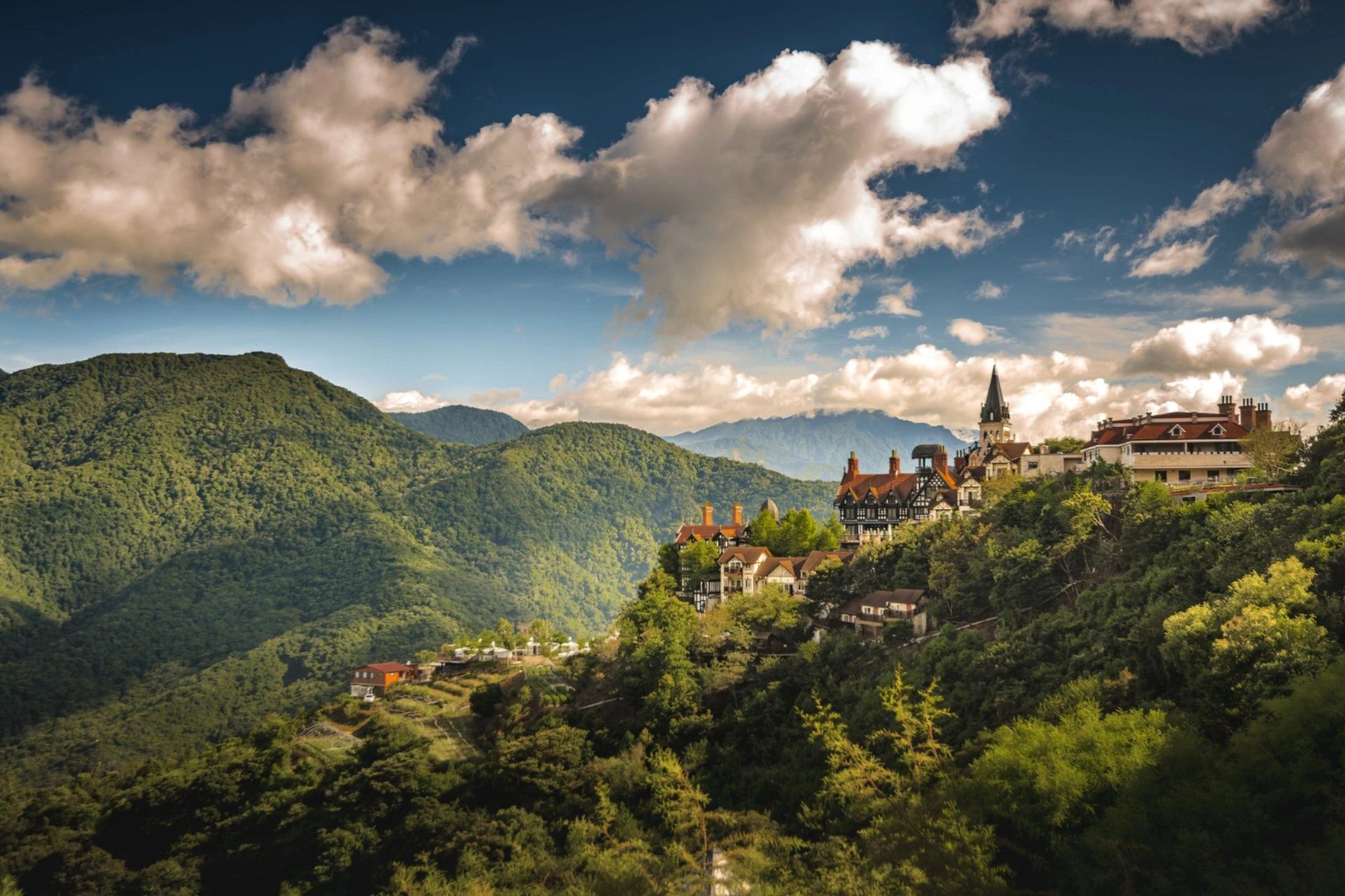 Scenic mountain landscape in Nepal with a hillside village, lush green hills, and dramatic clouds, perfect for a budget couple holiday in December.