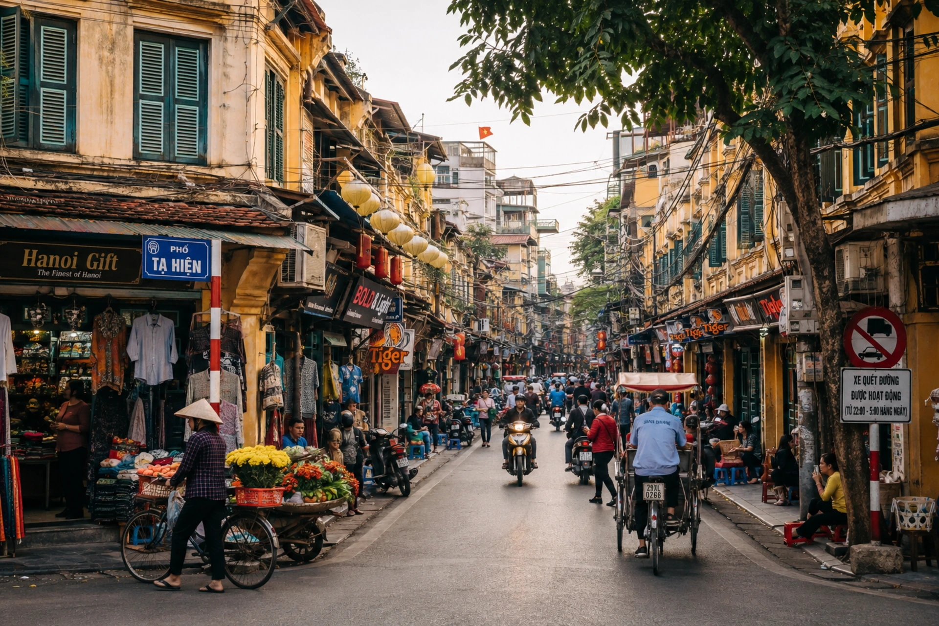 Hanoi Old Quarter street with yellow colonial buildings, shops, lanterns, scooters, and local vendors.